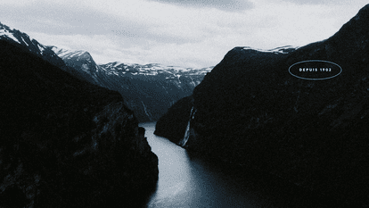 Panoramic view of a Norwegian fjord with steep mountains and a waterfall.