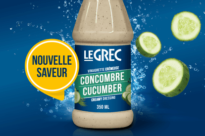 A 350 ml bottle of Le Grec's new creamy cucumber vinaigrette is presented on a blue background with cucumber slices surrounding it. The bottle's label is white with green accents, and the Le Grec logo is clearly visible at the top. A yellow band reads “No