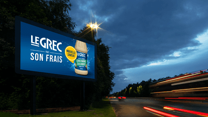 Un panneau d'affichage numérique au bord d'une autoroute fait la publicité de la nouvelle vinaigrette Le Grec au concombre. Le panneau affiche le logo Le Grec avec le slogan 