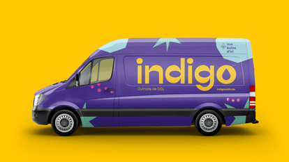 A purple delivery van with blue and pink motifs. The Indigo logo and the slogan “Your bubbles from here” are inscribed on the side. The words “CO₂ cylinder” indicate that this is a delivery vehicle for CO2 cylinders for sparkling water machines.