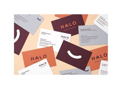 A collage of business cards for the Halo dental clinic. The cards feature the Halo logo, which is a stylized smile, and contact information for Dr. Maher Amoura, dentist, and Chantal Léonard, treatment plan coordinator. The cards are in a warm color palet