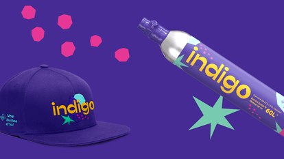 An Indigo cap and CO2 cylinder are set against a purple background decorated with geometric shapes and pink and blue bubbles. The cap is purple with the “indigo” logo embroidered in white and the phrase “Vos bulles d'ici” underneath. The cylinder is silve