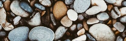 Close-up of an assortment of smooth, polished pebbles in shades of gray, brown and beige.