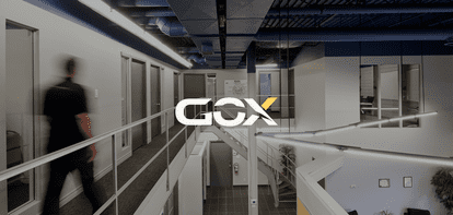 A blurred man walks down an office corridor with the GOX logo in the foreground.
